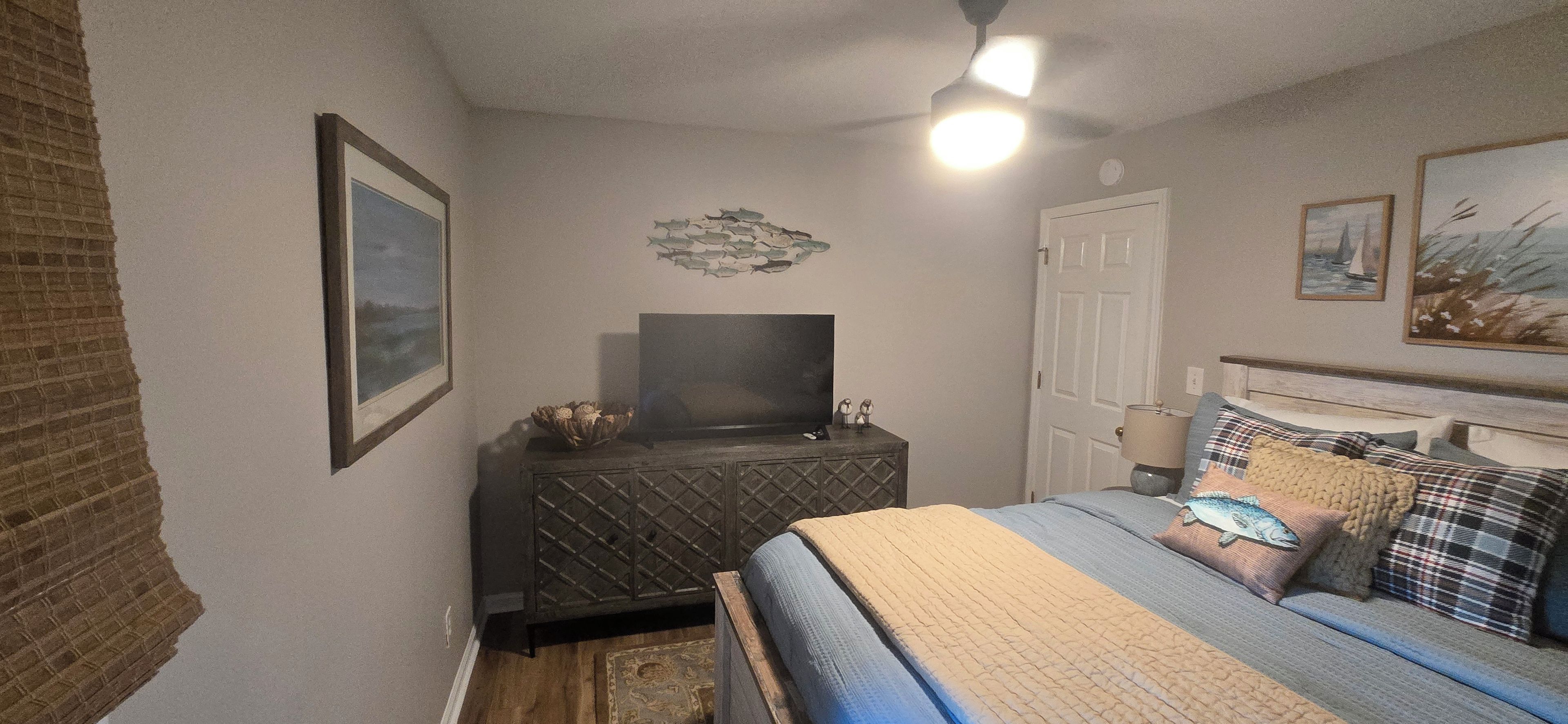 Een slaapkamer met een bed, een televisie, een deur en een decoratie aan de muur.