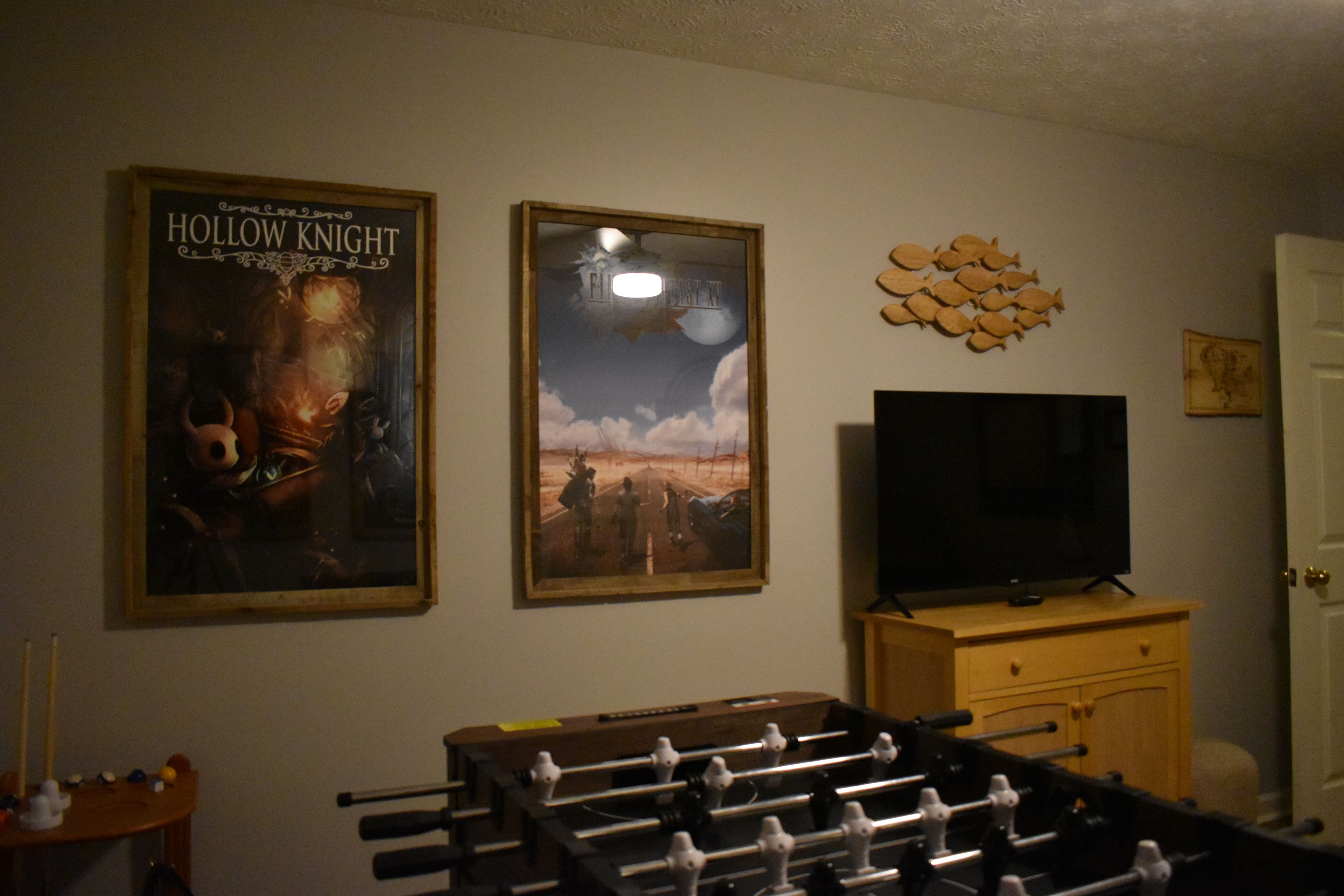 Ein Zimmer mit einem Kicker, einem Fernseher und zwei gerahmten Postern an der Wand.