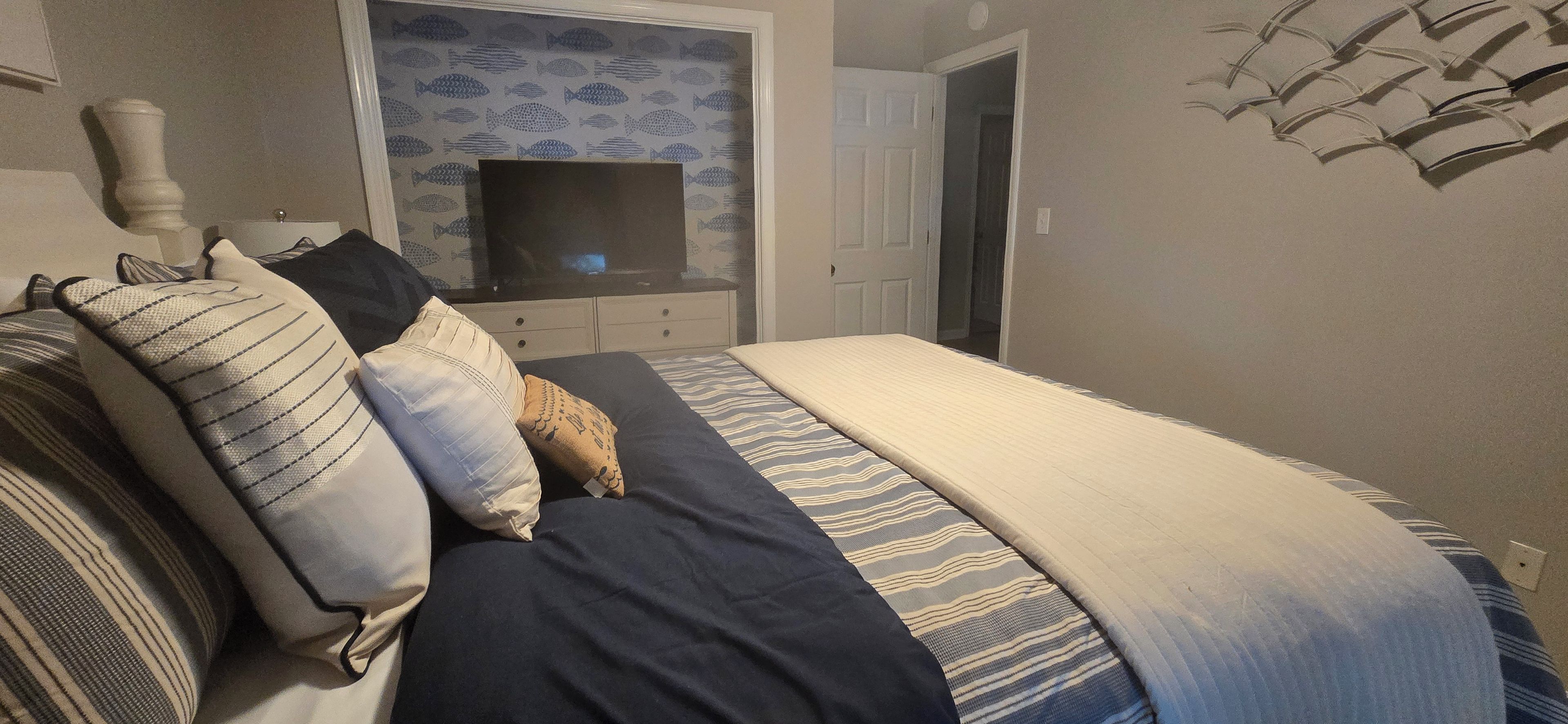 Ein Schlafzimmer mit Bett, Kissen, Fernseher und Tür.