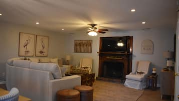 A living room with a fireplace, a ceiling fan, and a sofa.