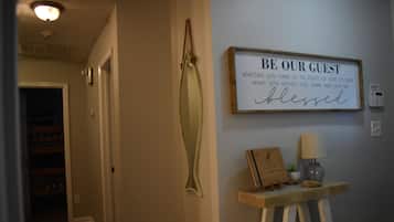 Een gang met een bord waarop staat: 'WEES ONZE GAST. Of u nu komt bezoeken of even uitrusten, moge u gezegend zijn bij het betreden van ons huis.'