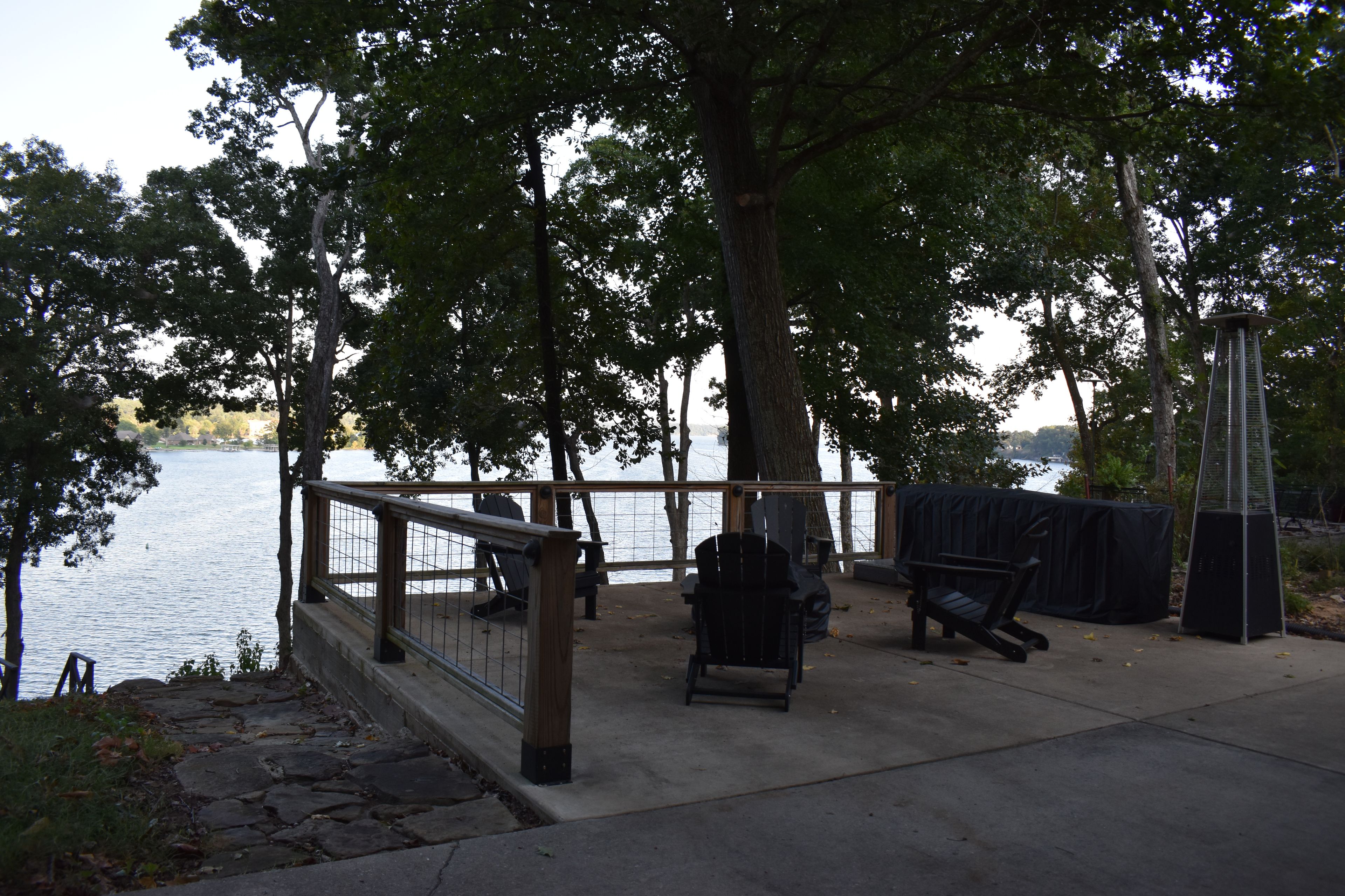Ein Park am Seeufer mit einer Holzterrasse, Adirondack-Stühlen und einem überdachten Grillbereich.