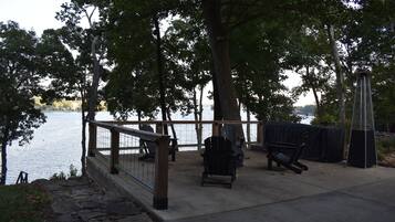Ein Park am Seeufer mit einer Holzterrasse, Adirondack-Stühlen und einem überdachten Grillbereich.