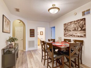A dining area with a wooden table, chairs, and a ceiling light fixture. - 2BR Condo Near Disney Resort Pool & Sauna (Kissimmee)