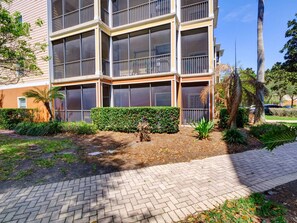 A multi-story building with balconies, a paved walkway, and landscaped areas with various plants. - 2BR Condo Near Disney Resort Pool & Sauna (Kissimmee)