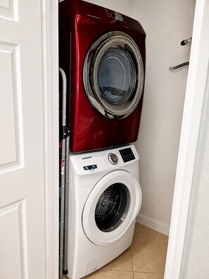Un área de lavandería compacta con lavadora y secadora apiladas, ambas de color rojo y blanco.
