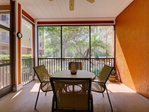 A balcony with a table and chairs, a potted plant, and a view of trees and buildings. - 2BR Condo Near Disney Resort Pool & Sauna (Kissimmee)