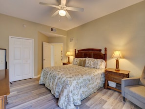 A bedroom with a bed, two bedside tables with lamps, a chair, a ceiling fan, and a door. - 2BR Condo Near Disney Resort Pool & Sauna (Kissimmee)