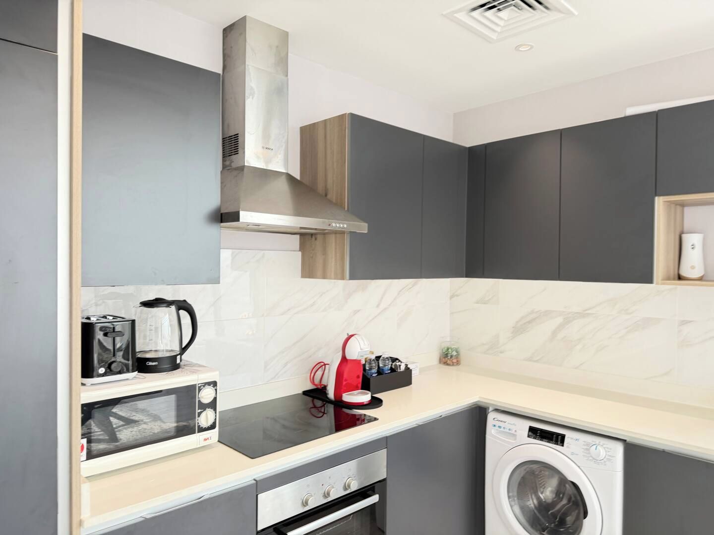 A compact kitchen with a built-in oven, microwave, and a washing machine.