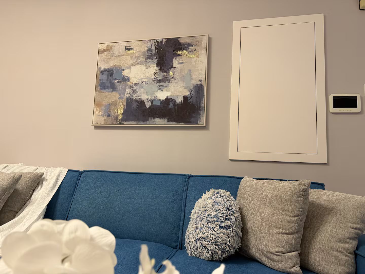 A modern living room with a blue sofa, decorative pillows, and abstract wall art.