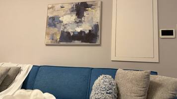 A modern living room with a blue sofa, decorative pillows, and abstract wall art.