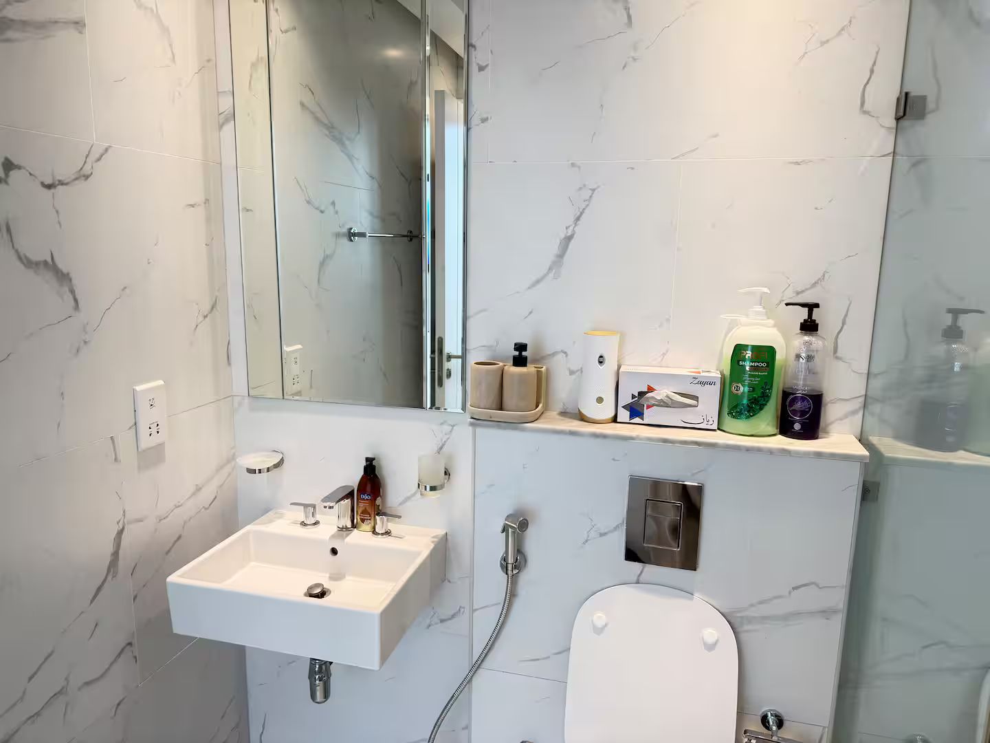 A bathroom with a white sink, a toilet, a shower, and a mirror.
