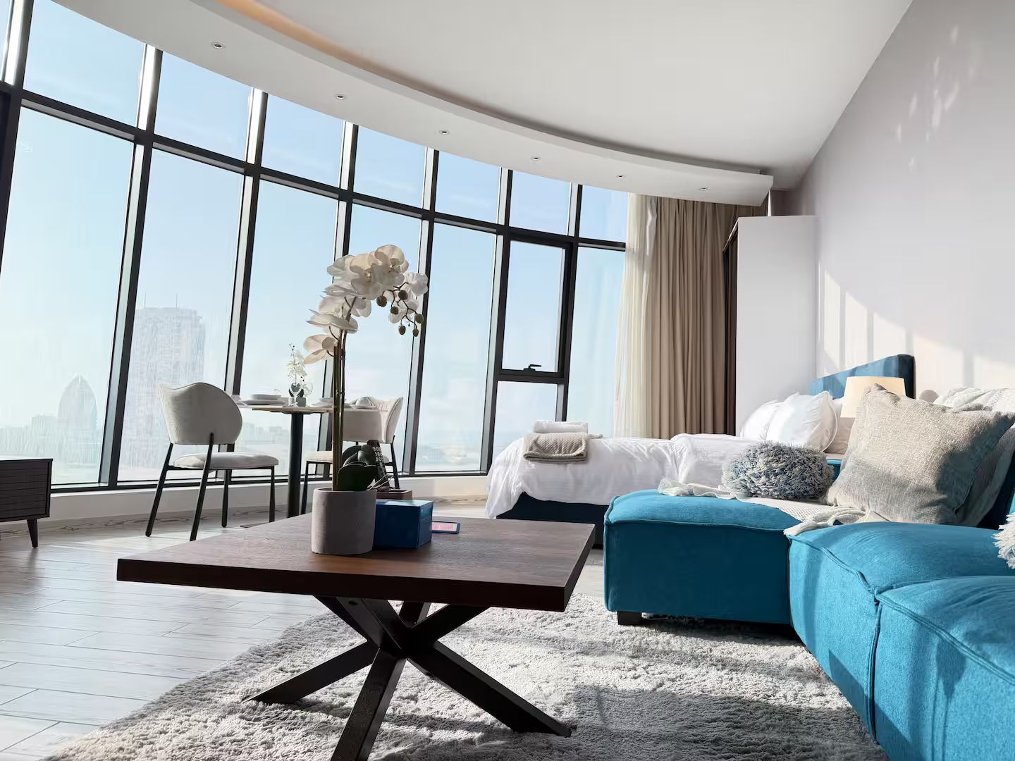 Et moderne hotelværelse med et stort vindue, en sofa, et sofabord og en lænestol.