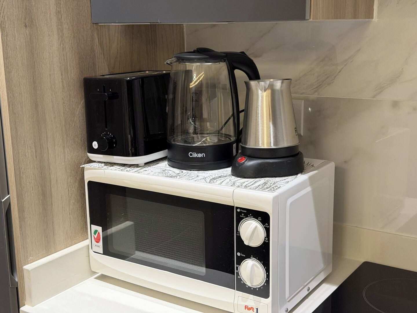 A compact kitchen with a microwave, toaster, and coffee maker on a countertop.
