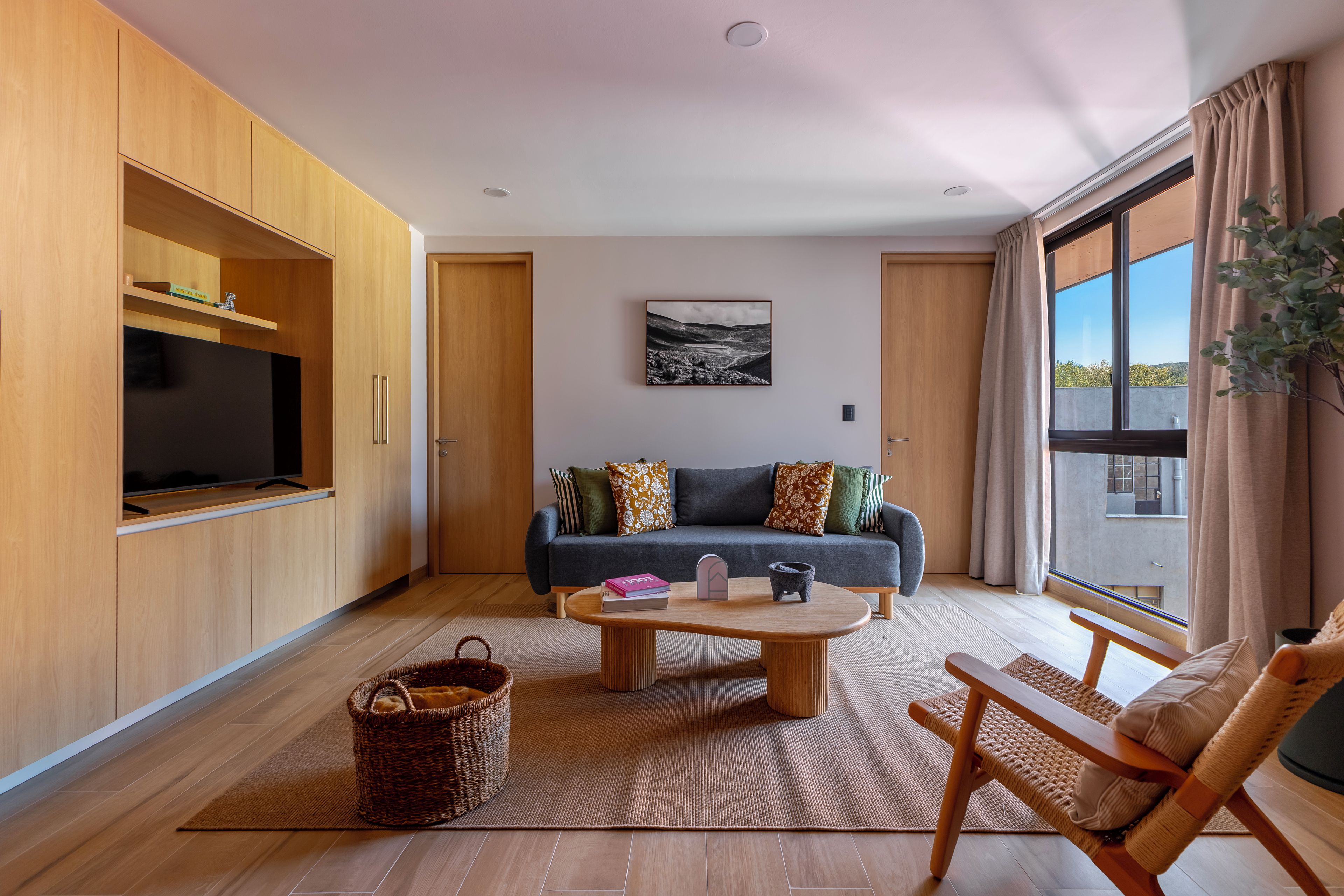 A modern living room with a sofa, coffee table, and a TV mounted on a wooden cabinet.