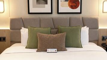 A neatly made bed with a pillow and a remote control, a headboard with two framed artworks, and bedside lamps.