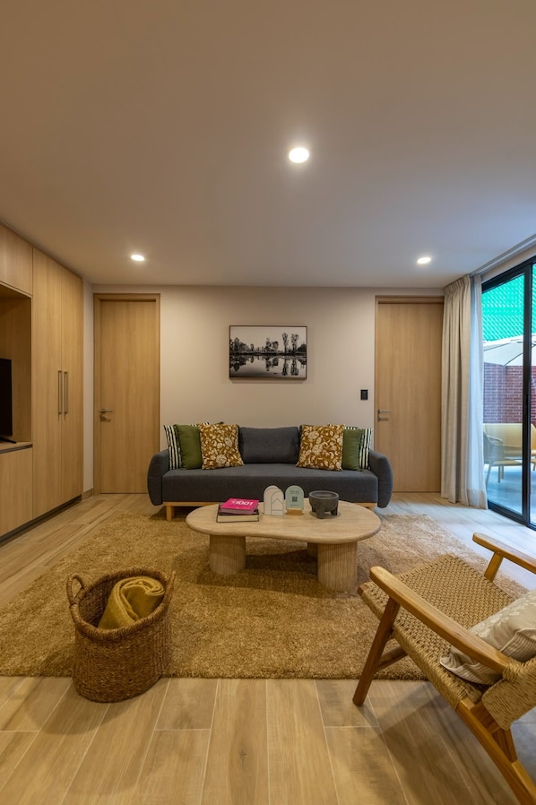 A modern living room with a sofa, coffee table, and a painting on the wall. - Capitalia Reforma (Ciudad de México)