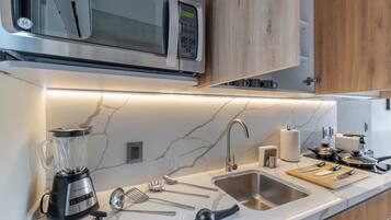 A modern kitchen with a built-in microwave, a blender, a sink, and various utensils.