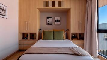 A bedroom with a bed, wooden cabinets, a window, and artwork on the wall.