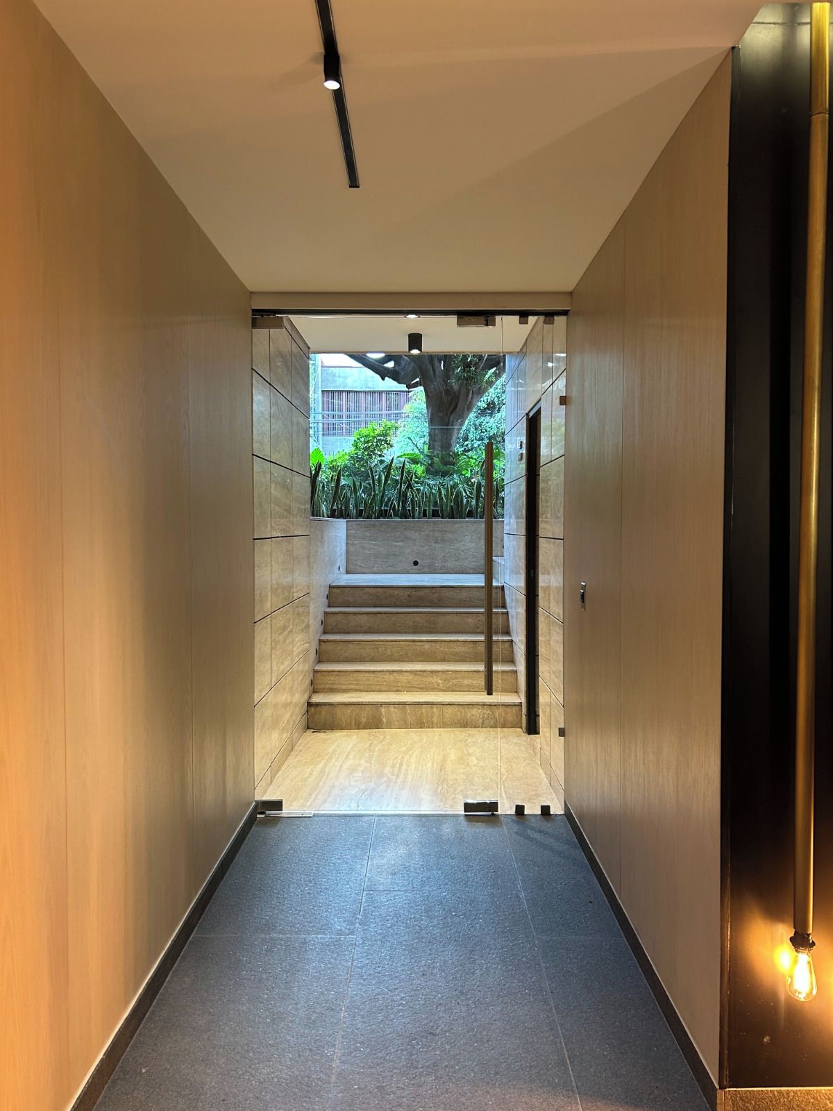 A modern interior corridor with a staircase leading to an outdoor area.