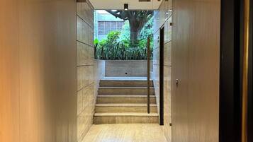 A modern interior corridor with a staircase leading to an outdoor area.