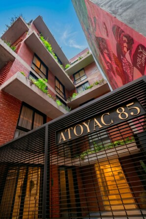 Un edificio con un letrero que dice 'ATOYAC 85' y balcones con plantas.