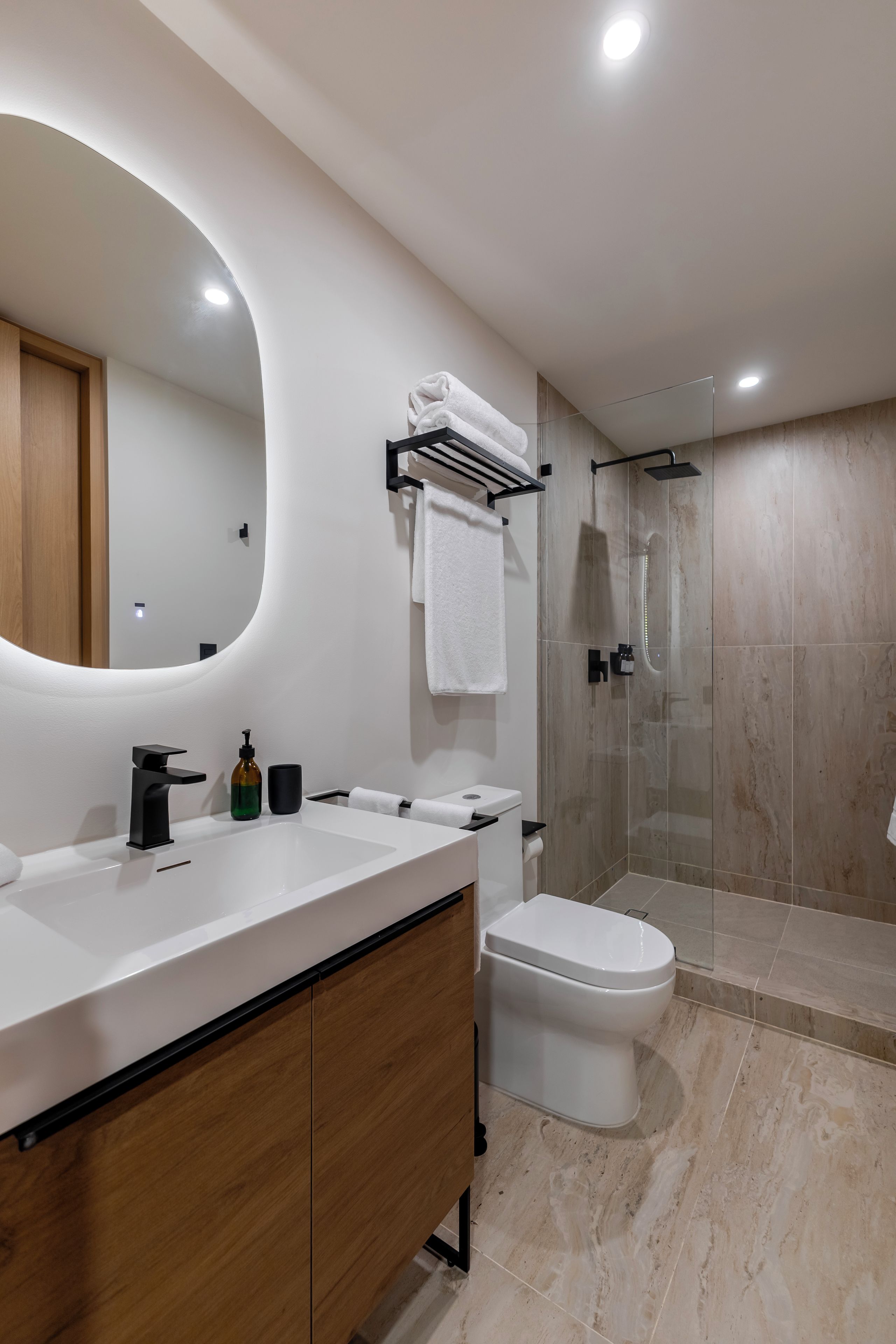 Une salle de bain moderne avec un grand miroir, des toilettes, une douche et un meuble-lavabo.
