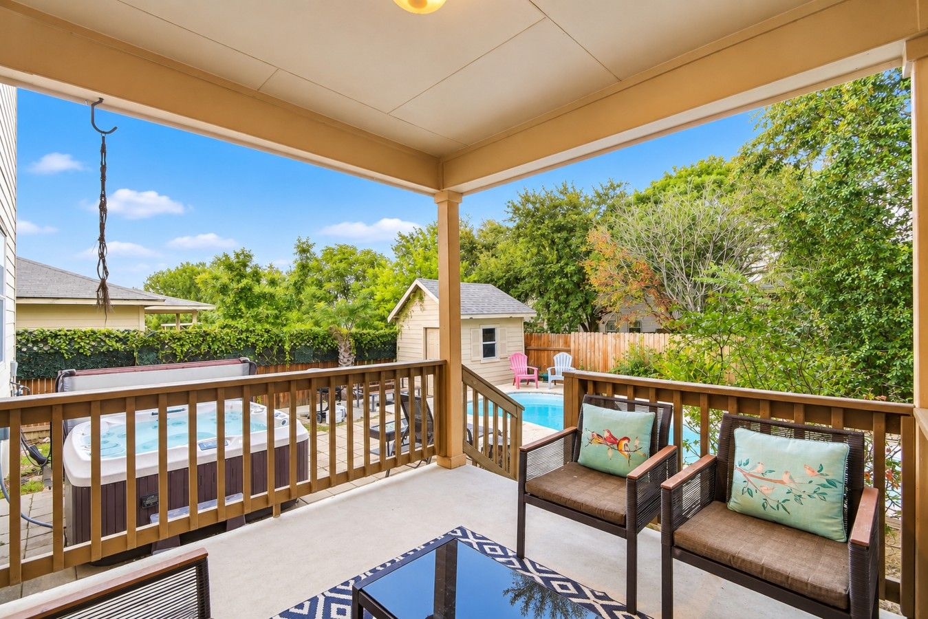 Un patio couvert avec une piscine, du mobilier d’extérieur et une vue sur le jardin arrière.
