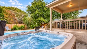 A hot tub with a wooden deck and a covered seating area.