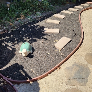 A garden area with mulch, stepping stones, a garden hose, and a turtle statue. - Just 0.6 mile to Center of Ojai, this beautiful 3-2 home is calling you. (Ojai)