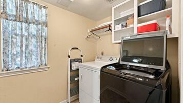 A laundry room with a washing machine, dryer, and a utility cart.