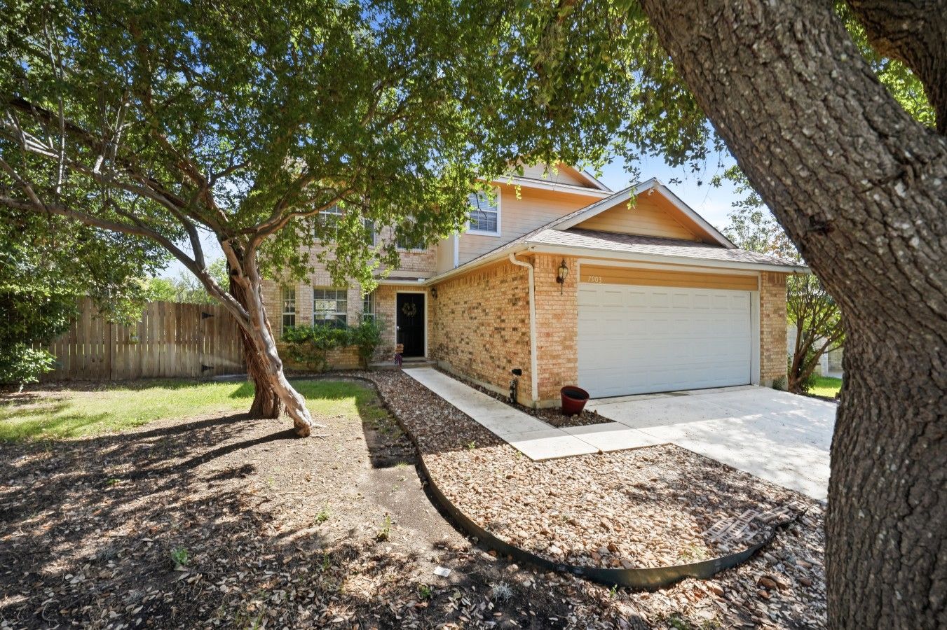 A residential property with a brick exterior, a garage, and a driveway leading to the entrance.