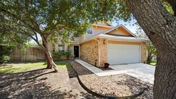 A residential property with a brick exterior, a garage, and a driveway leading to the entrance.