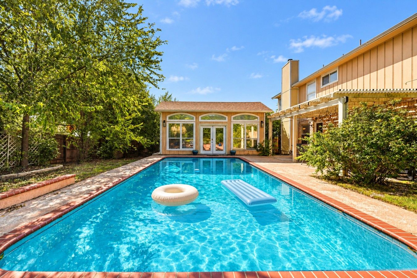A rectangular swimming pool with a clear blue water surface, surrounded by a brick border.