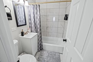 Ein Badezimmer mit Toilette, Waschbecken, Dusche und einem Handtuchhalter.