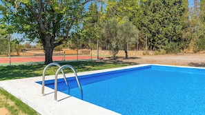 A rectangular swimming pool with a white edge and metal ladder, surrounded by a grassy area and trees. - Heredad La Encarnación Ronda by Ruralidays (Málaga)