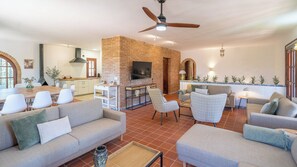 Amplia sala de estar con chimenea de ladrillo, televisión y asientos cómodos.