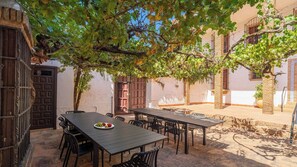 An outdoor patio with tables and chairs, surrounded by buildings with traditional architecture. - Heredad La Encarnación Ronda by Ruralidays (Málaga)