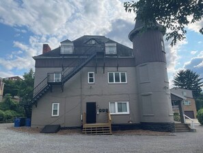 Een meerhoog gebouw met een centraal torentje, een trap en een deur.