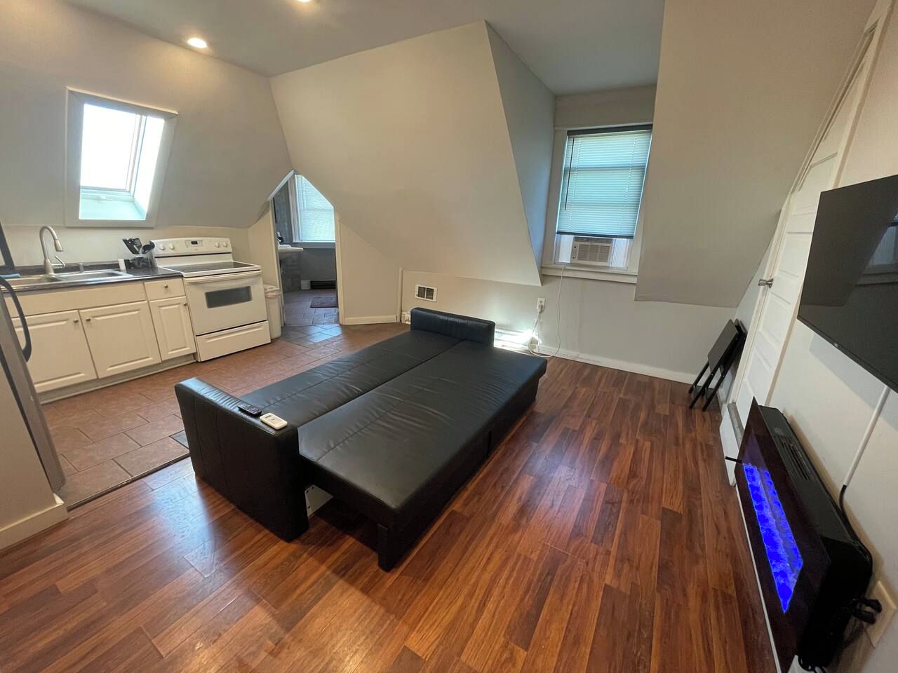 A compact room with a kitchenette, a bed, and a television.