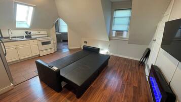 A compact room with a kitchenette, a bed, and a television.