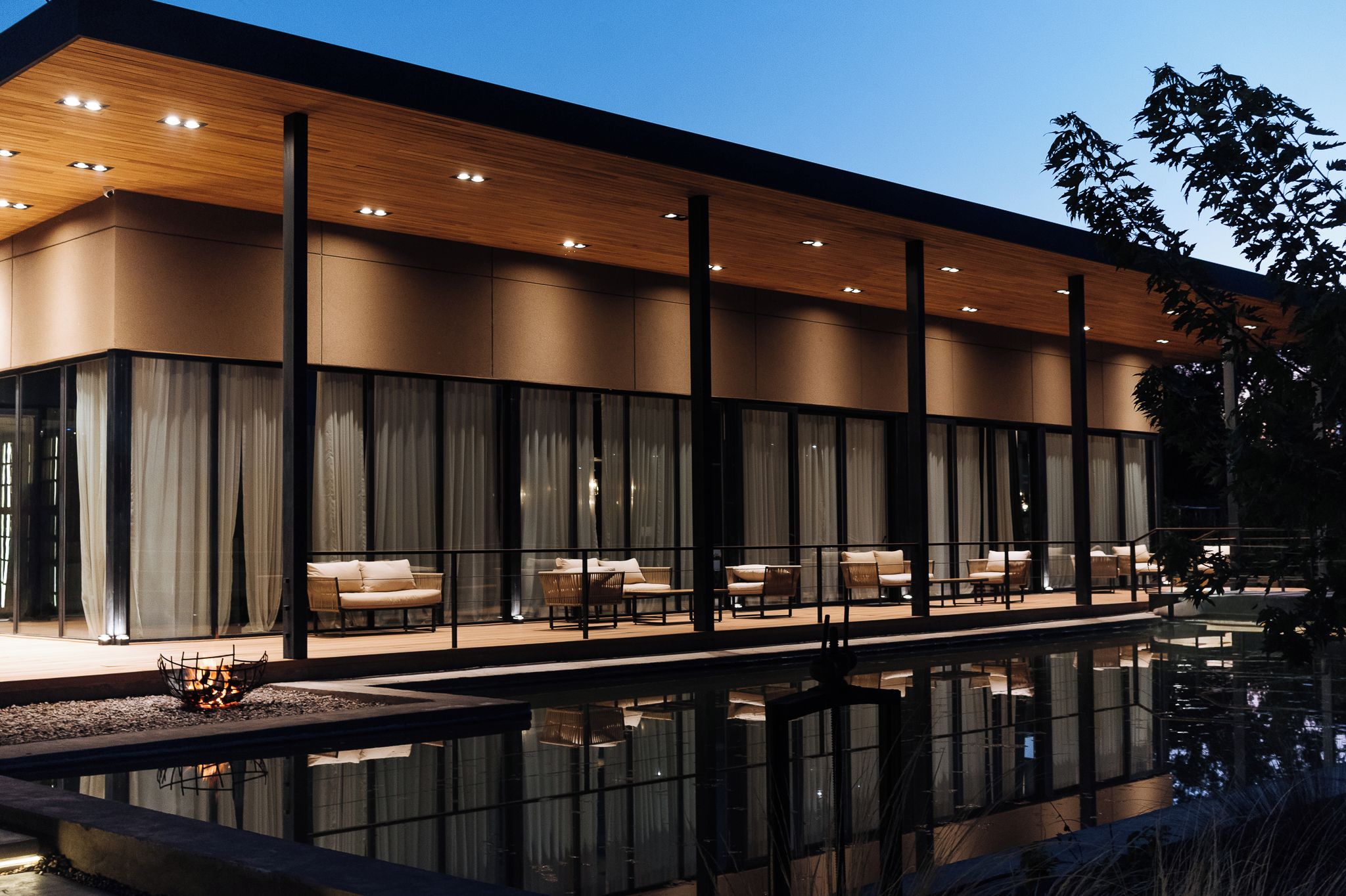 Un edificio moderno con piscina, ventanas amplias y zona de estar al aire libre.