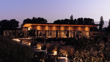 A modern building with a flat roof and large windows, surrounded by a landscaped garden with pathways and plants.