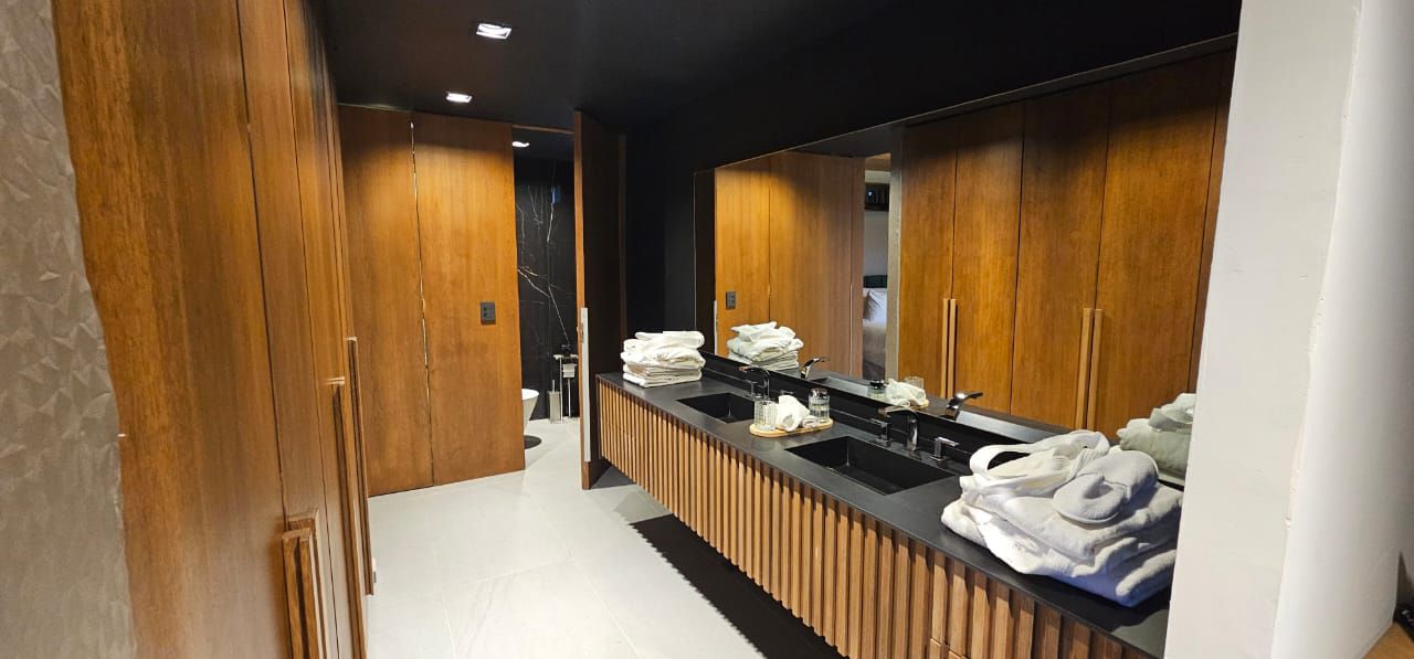 A modern bathroom with wooden cabinets, a black countertop, and a large mirror.