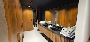 A modern bathroom with wooden cabinets, a black countertop, and a large mirror. - Legado Wine Lodge (Maipú)