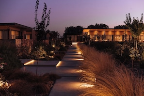 Un camí que condueix a un edifici modern amb una entrada ben il·luminada i zones enjardinades al voltant.
