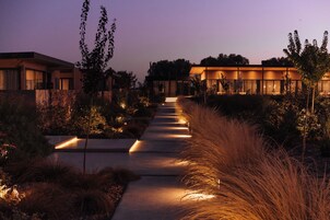 Un sendero conduce a un edificio moderno con una entrada bien iluminada y zonas ajardinadas.