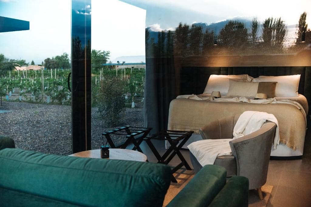 Un dormitorio con cama, un sofá verde y vistas a un jardín y montañas.
