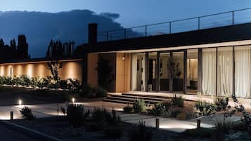 Ein modernes Haus mit Glasfassade, einem gut beleuchteten Eingangsbereich und einem angelegten Garten.