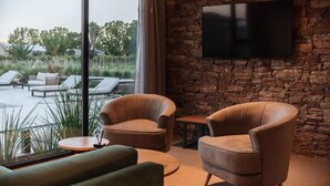 Un área de estar con sillones de cuero, un sofá y un televisor de pantalla plana montado en una pared de piedra.